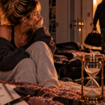 Woman sitting beside an hourglass as a man leaves with his belongings, representing the realization that she stayed long enough, gave enough time, and is finally ready to choose herself and move forward.