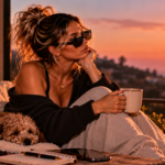 Woman sitting quietly with her dog overlooking the coast at sunset, representing the kind of personal growth that happens when you stop explaining yourself, move in silence, and let your changed choices speak for you.