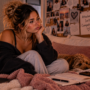 Woman sitting thoughtfully on her bed surrounded by reminders of past relationships, reflecting on the realization that feeling deeply attached to someone doesn’t necessarily mean they’re compatible with you.